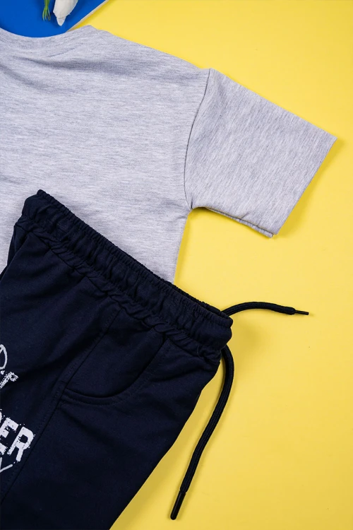 طقم ولادي قطعتين تيشيرت لون رمادي مزين بكتابات و رسومات مع شورت لون كحلي برباط في الوسط و جيوب من الجانبين