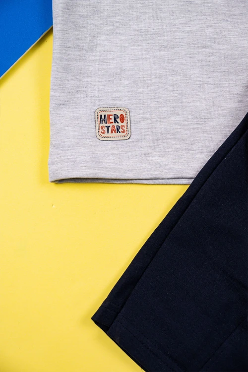 طقم ولادي قطعتين تيشيرت لون رمادي مزين بكتابات و رسومات مع شورت لون كحلي برباط في الوسط و جيوب من الجانبين