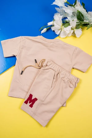 طقم ولادي قطعتين لون بيج تيشيرت بكتابات و رسومات من الأمام مع شورت برباط في الوسط و جيوب من الجانبين