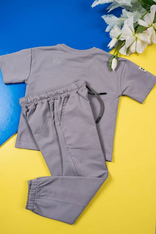 طقم ولادي قطعتين لون رصاصي تيشيرت بكتابات من الأمام مع بنطلون طويل برباط في الوسط و زم في الأسفل و جيوب من الجانبين