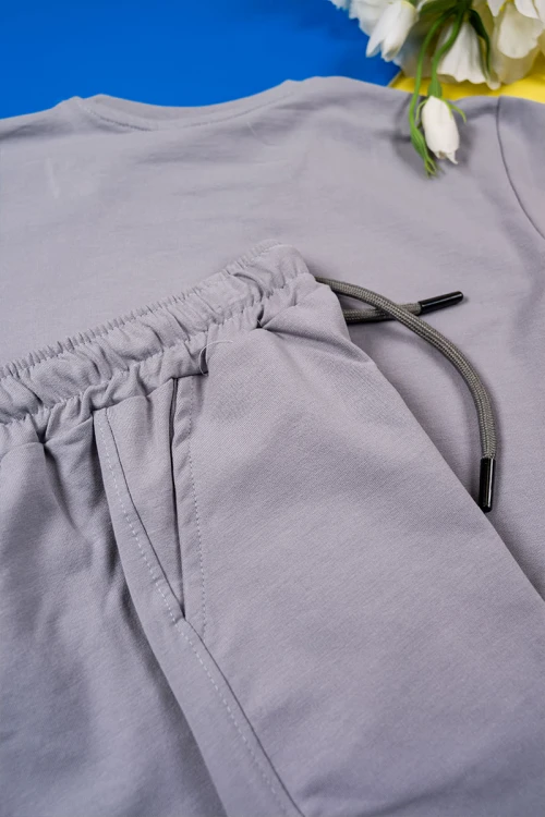 طقم ولادي قطعتين لون رصاصي تيشيرت بكتابات من الأمام مع بنطلون طويل برباط في الوسط و زم في الأسفل و جيوب من الجانبين