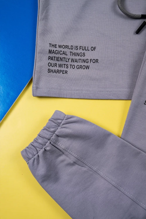 طقم ولادي قطعتين لون رصاصي تيشيرت بكتابات من الأمام مع بنطلون طويل برباط في الوسط و زم في الأسفل و جيوب من الجانبين