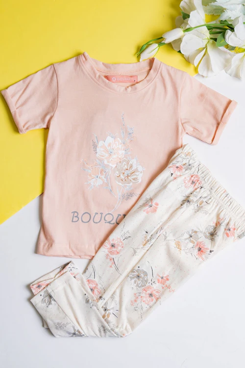 بيجاما بناتي قطعتين تيشيرت لون خربزي مزين برسومات و كتابات من الأمام مع بنطلون بيج فاتح مشجر
