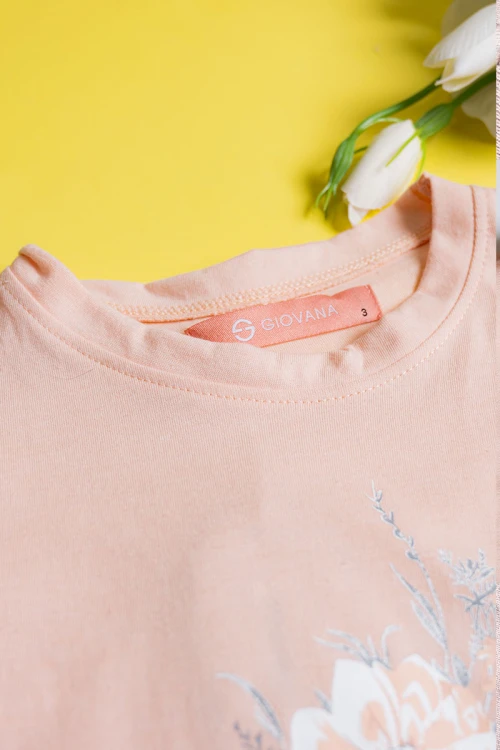 بيجاما بناتي قطعتين تيشيرت لون خربزي مزين برسومات و كتابات من الأمام مع بنطلون بيج فاتح مشجر