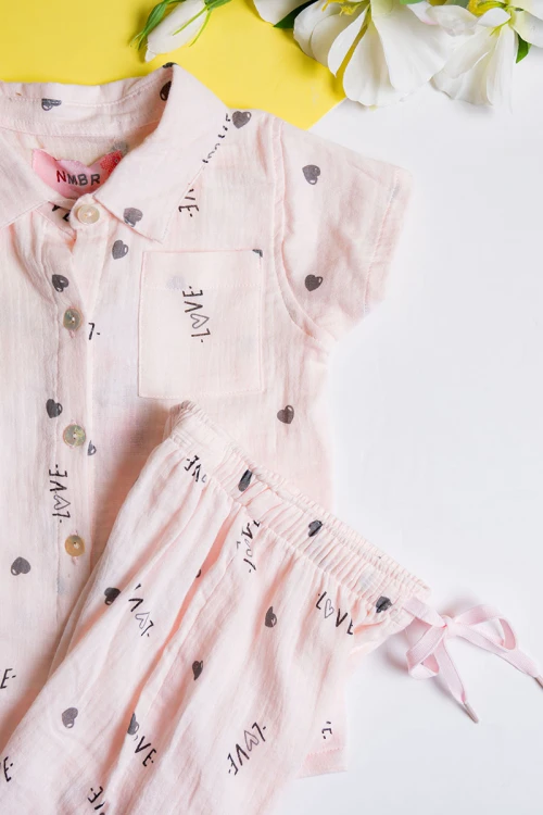 بيجاما بناتي قطعتين لون خربزي مزين برسومات و كتابات تيشيرت بياقة مطوية و أزرار من الأمام مع بنطلون طويل برباط في الخصر