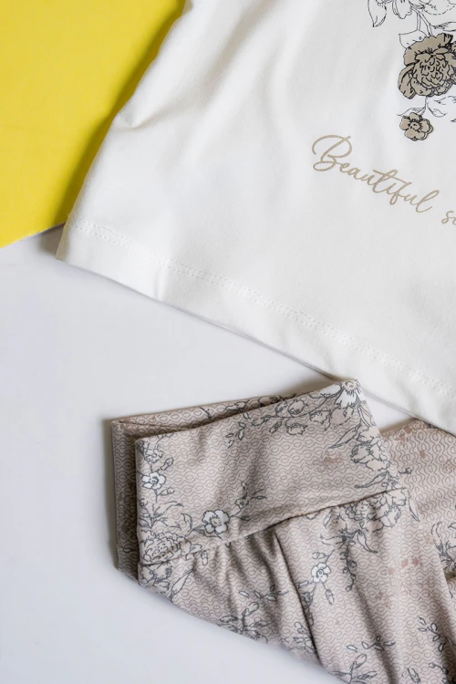 بيجاما بناتي قطعتين تيشيرت لون أبيض مزين برسومات و كتابات من الأمام مع بنطلون طويل لون بيج مشجر