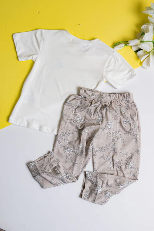 بيجاما بناتي قطعتين تيشيرت لون أبيض مزين برسومات و كتابات من الأمام مع بنطلون طويل لون بيج مشجر