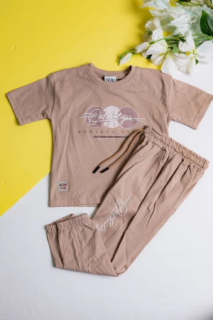 طقم ولادي قطعتين لون بيج تيشيرت مزين بكتابات و رسومات من الأمام مع بنطلون طويل بجيوب و رباط في الخصر 