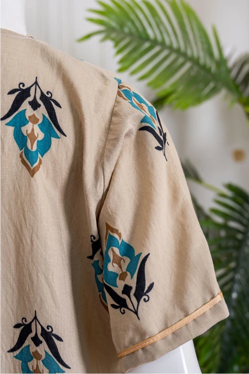 جلابية نسائية لون بيج مزينة بزخارف ملونة ياقة بقصة سبعة بكلفة مطرزة باللون الذهبي من الياقة و بأكمام قصيرة