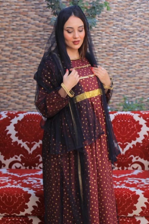 فستان تراثي نسائي أنيق قطعتين لون عودي بتطريز وطبعات لامعة باللون الذهبي مع عباية شفافة باللون الأسود